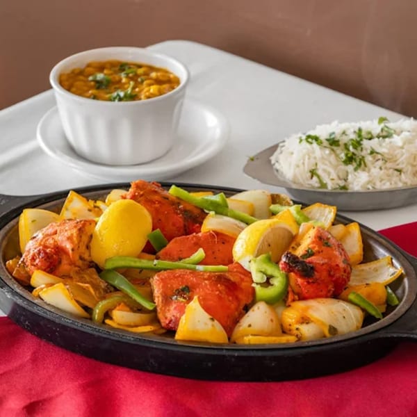 Sizzling chicken tikka with onions, peppers, and lemons, served with rice and dal.